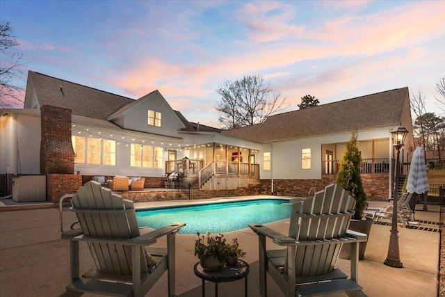 pool at dusk featuring a patio and an outdoor pool