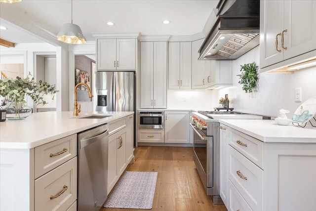 kitchen featuring light countertops, custom range hood, appliances with stainless steel finishes, and a sink