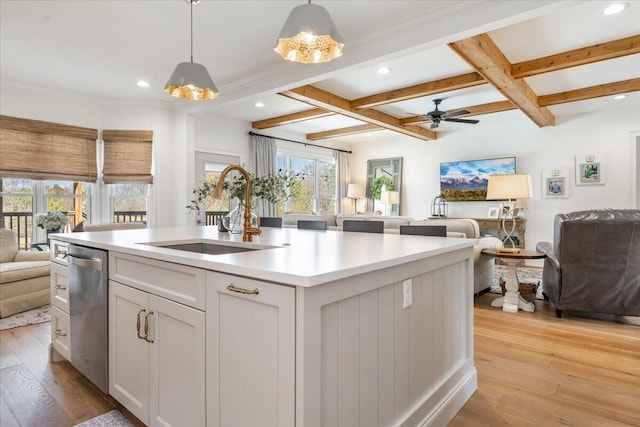 kitchen featuring open floor plan, dishwasher, beam ceiling, light wood-style flooring, and a sink