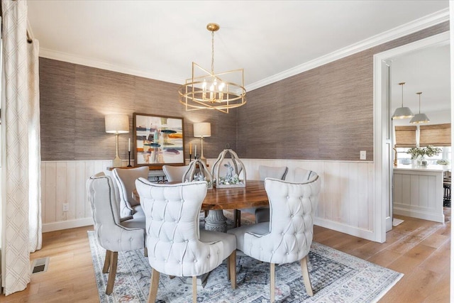 dining area featuring a wainscoted wall, visible vents, wallpapered walls, ornamental molding, and a notable chandelier