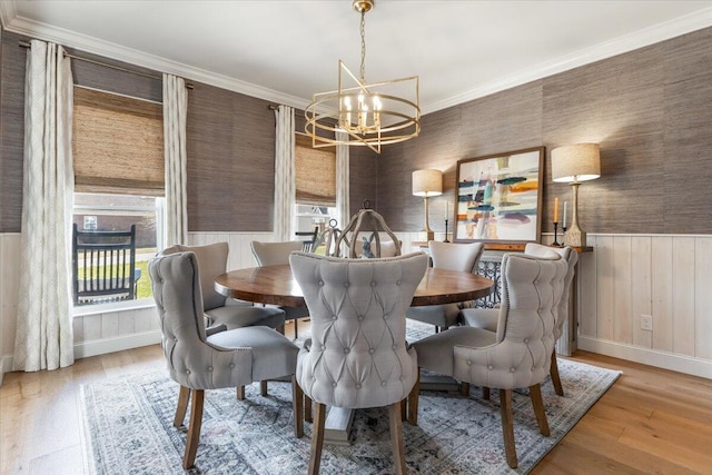 dining space with wallpapered walls, wood finished floors, an inviting chandelier, and ornamental molding