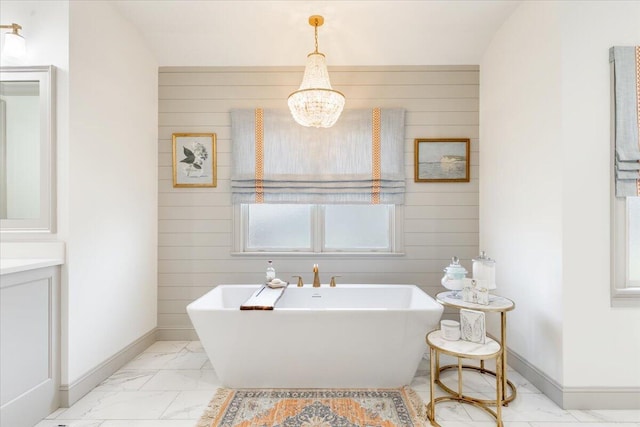 bathroom with baseboards, a soaking tub, marble finish floor, and wooden walls