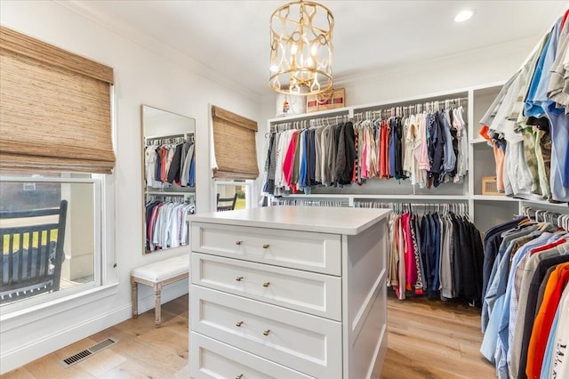 walk in closet with a notable chandelier, visible vents, and light wood finished floors