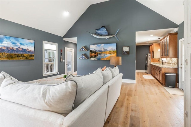 living area with baseboards, light wood-style floors, and high vaulted ceiling