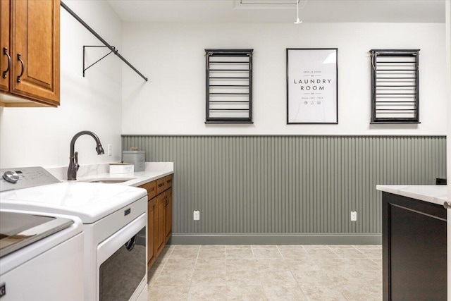 laundry room with light tile patterned floors, washing machine and clothes dryer, cabinet space, a sink, and wainscoting