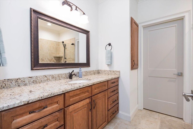 bathroom featuring a tile shower, tile patterned flooring, vanity, and baseboards