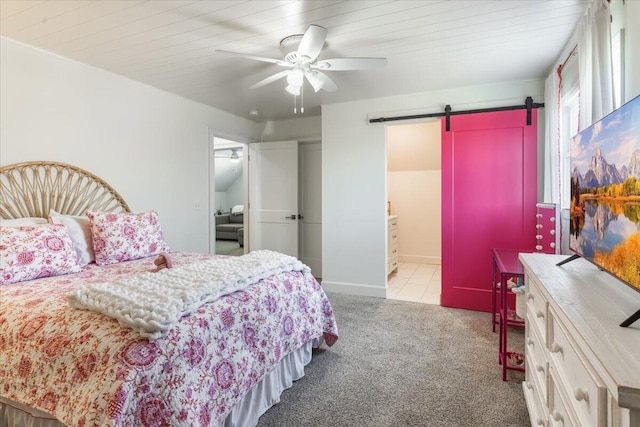 bedroom featuring a ceiling fan, carpet, baseboards, a barn door, and connected bathroom