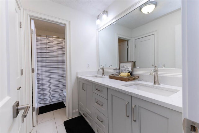 bathroom with double vanity, marble finish floor, a textured ceiling, and a sink