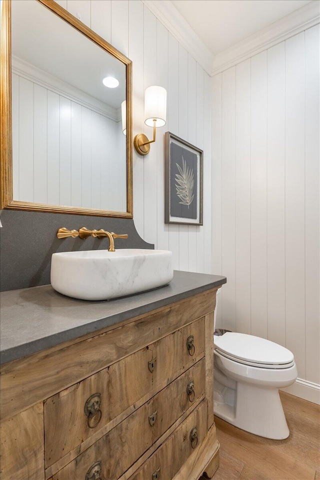 bathroom with wood finished floors, toilet, ornamental molding, and vanity