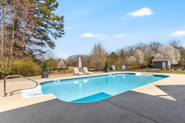 view of swimming pool with a fenced in pool, an outbuilding, fence, and a patio area