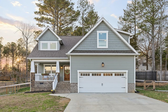 craftsman house featuring covered porch, concrete driveway, roof with shingles, and fence