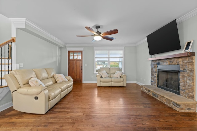 living area featuring wood finished floors, a stone fireplace, ceiling fan, and ornamental molding