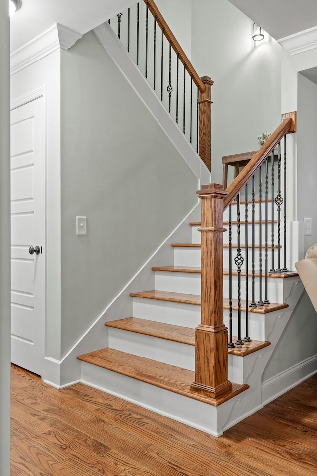 stairway featuring wood finished floors, baseboards, and ornamental molding