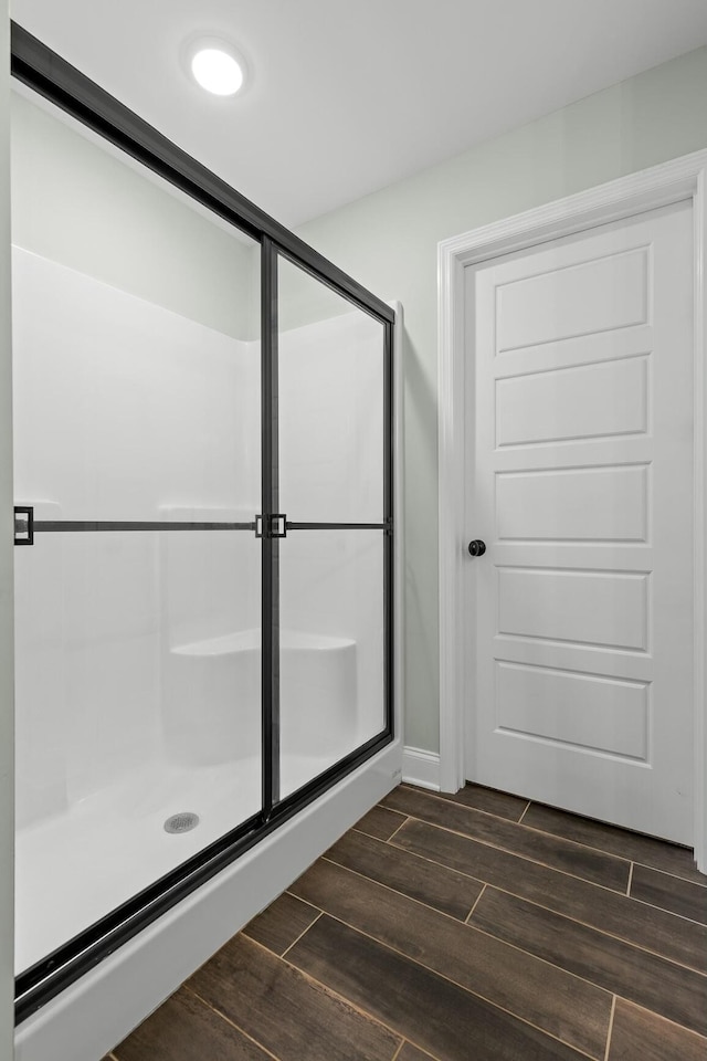 bathroom with a shower stall and wood finish floors