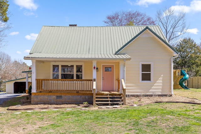 view of front of home featuring a front lawn, a playground, covered porch, metal roof, and a chimney