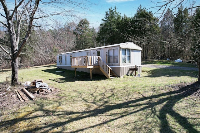 rear view of house with a wooden deck and a lawn