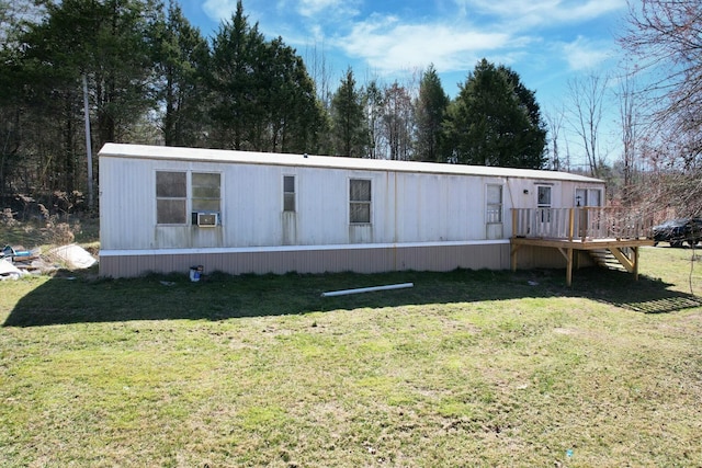 manufactured / mobile home with cooling unit, a wooden deck, and a front lawn