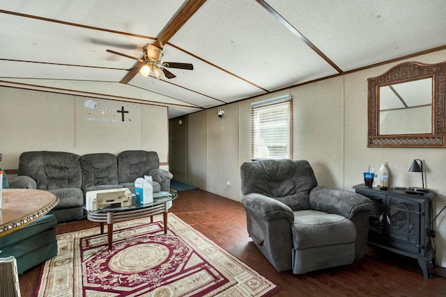 living area with vaulted ceiling with beams, a wood stove, a ceiling fan, and wood finished floors