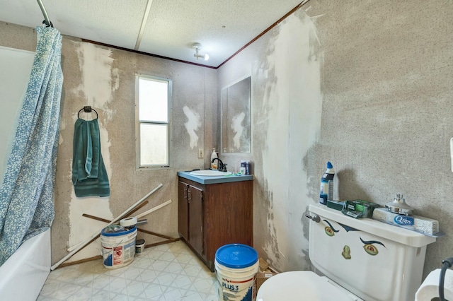 bathroom with tile patterned floors, toilet, a textured ceiling, crown molding, and vanity