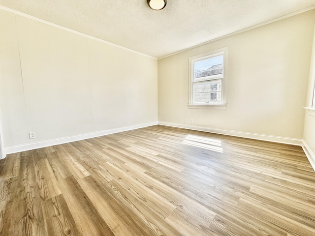 empty room with baseboards, a textured ceiling, wood finished floors, and crown molding