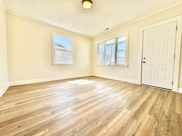 foyer featuring visible vents, light wood-style flooring, a textured ceiling, and ornamental molding