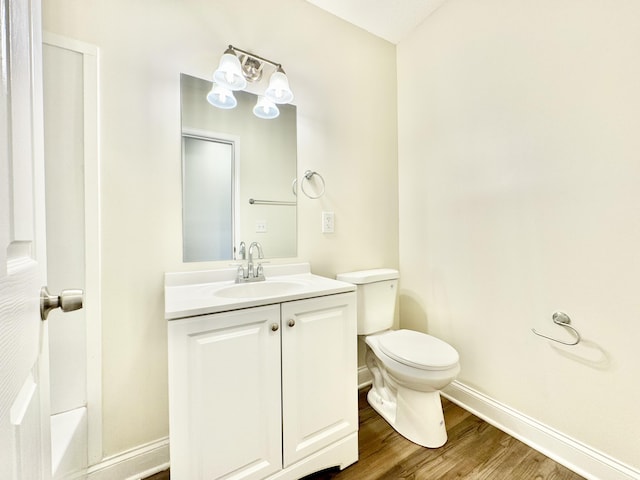 bathroom featuring vanity, toilet, wood finished floors, and baseboards