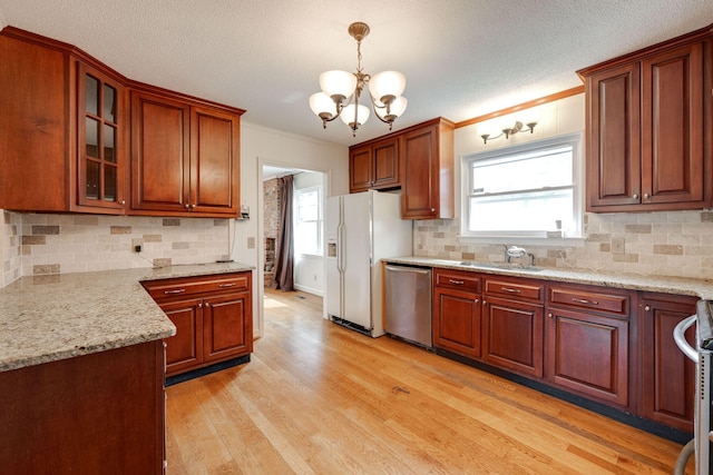 kitchen with a sink, ornamental molding, light wood finished floors, and stainless steel appliances