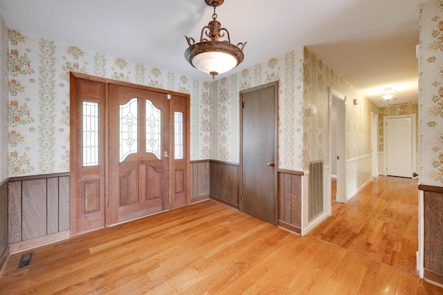 foyer featuring wallpapered walls, visible vents, and a wainscoted wall