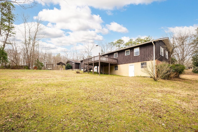 back of house featuring a wooden deck, a yard, and a chimney