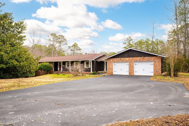 ranch-style house with brick siding, covered porch, a garage, aphalt driveway, and board and batten siding