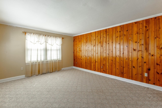 spare room featuring crown molding, baseboards, and wood walls