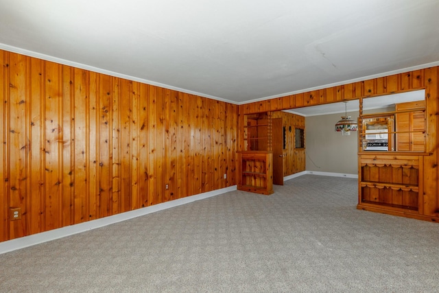 unfurnished room with baseboards, carpet flooring, wooden walls, and crown molding