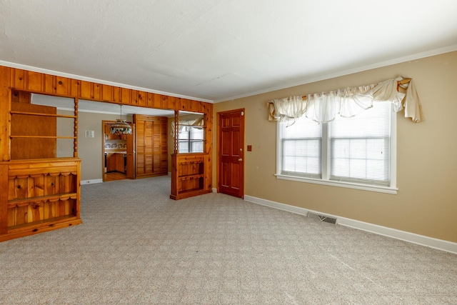 carpeted spare room featuring baseboards and ornamental molding