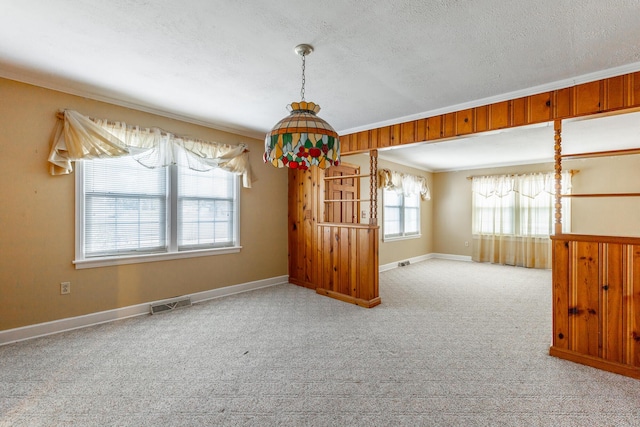 unfurnished room with carpet, a textured ceiling, baseboards, visible vents, and ornamental molding