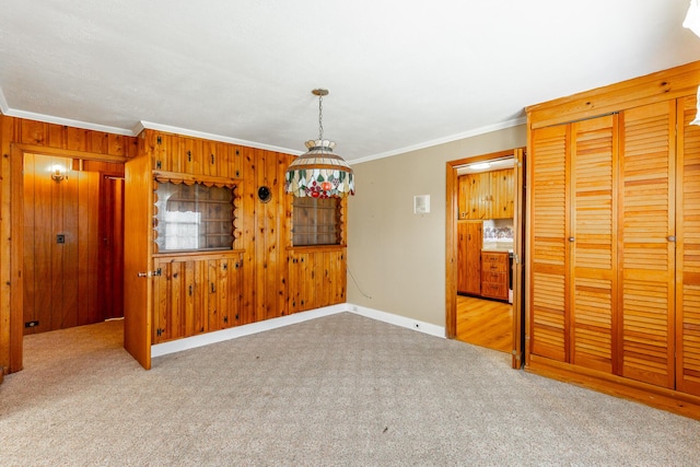 carpeted empty room with baseboards, ornamental molding, and wood walls