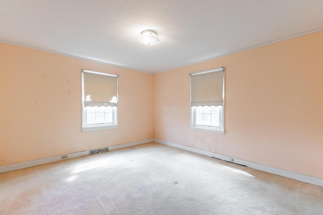 unfurnished room with baseboards, carpet floors, visible vents, and crown molding