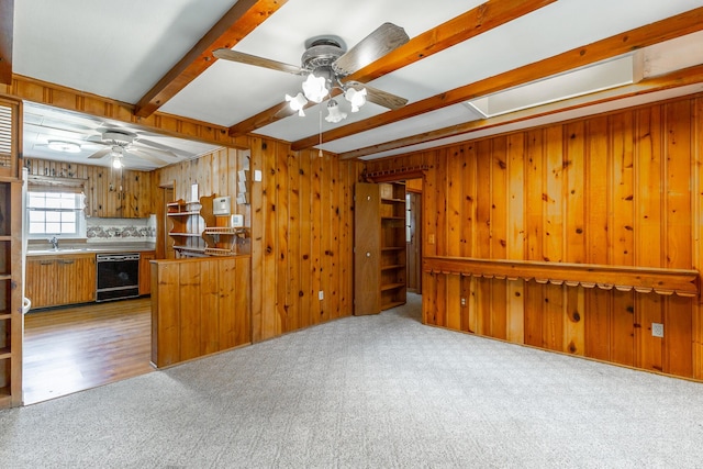unfurnished living room with ceiling fan, wood walls, and beamed ceiling