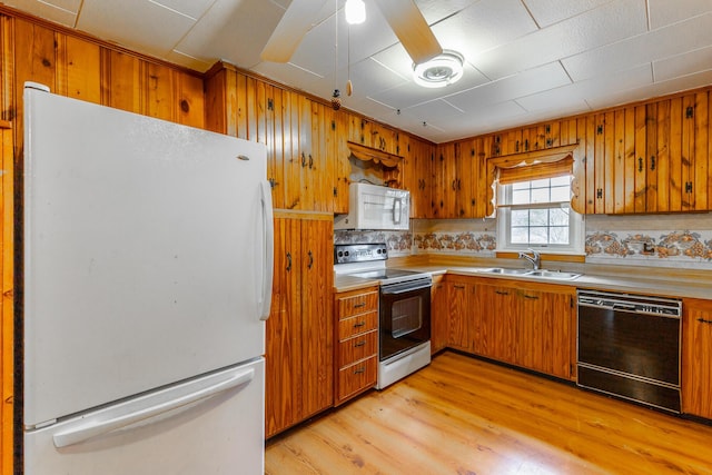 kitchen featuring light countertops, white appliances, a sink, light wood finished floors, and brown cabinetry