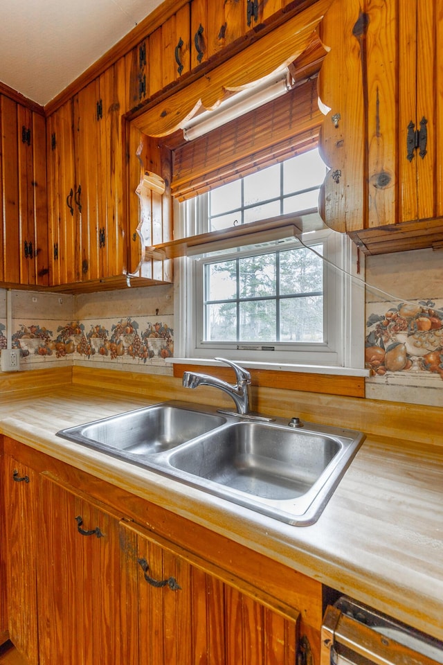 kitchen with light countertops, a sink, and brown cabinets