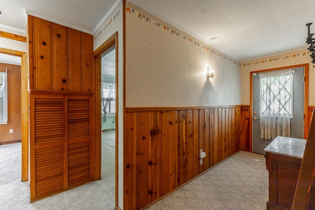 corridor with wallpapered walls, carpet floors, ornamental molding, and wainscoting