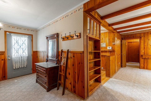 foyer with beamed ceiling, wallpapered walls, wainscoting, and light colored carpet