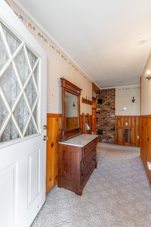 interior space featuring wallpapered walls, wainscoting, and light colored carpet