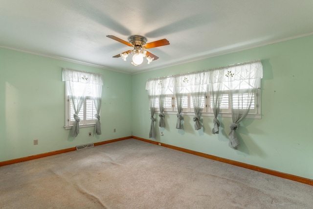 empty room featuring a ceiling fan, carpet floors, plenty of natural light, and visible vents