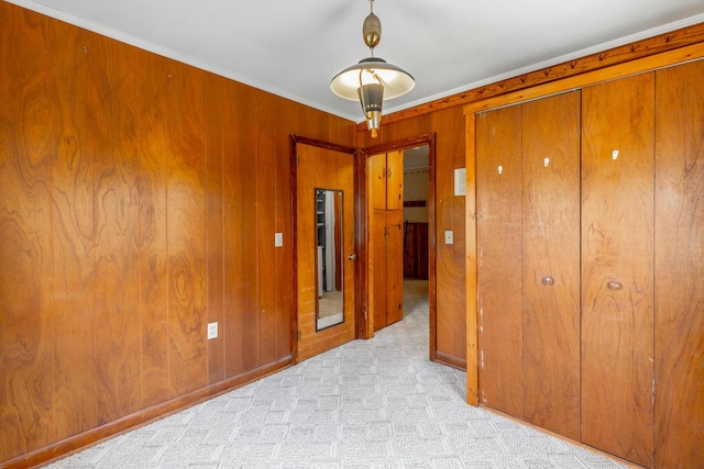 unfurnished bedroom with a closet, wooden walls, and light colored carpet