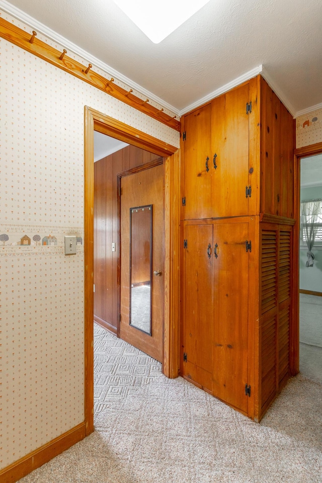 hallway featuring crown molding and light carpet
