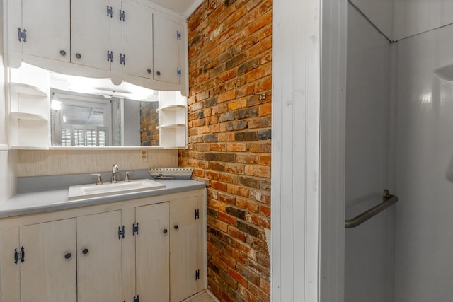 kitchen featuring light countertops, white cabinets, a sink, open shelves, and brick wall