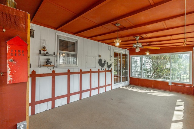 unfurnished sunroom featuring ceiling fan and beam ceiling