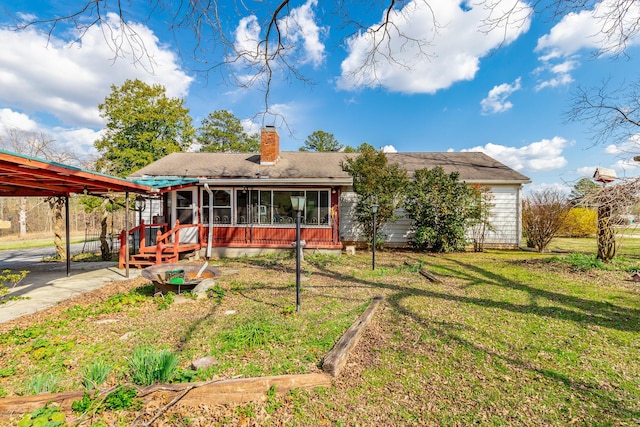 back of property with a chimney, a sunroom, and a yard