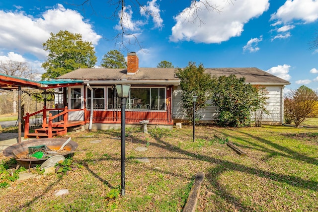 back of house featuring a chimney, a sunroom, and a yard