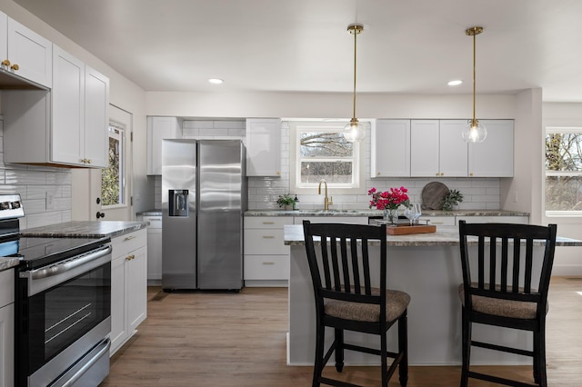 kitchen with a sink, stainless steel appliances, plenty of natural light, and light wood-style floors